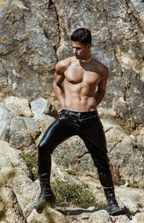 A Man Standing On Top Of A Rock Next To A Rocky Hillside With His Shirt Off