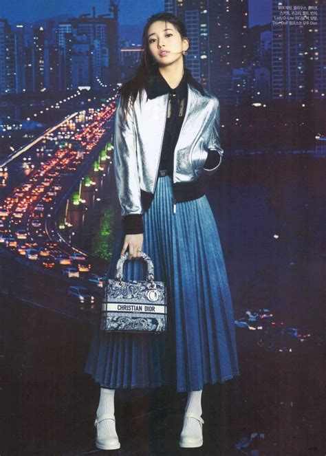 A Woman In A Blue Pleated Skirt Holding A Purse