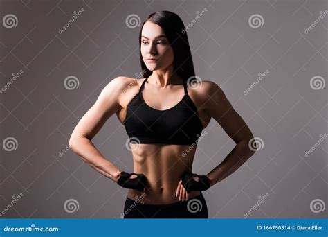 Portrait Of Beautiful Sporty Woman With Muscular Body Posing Over Gray