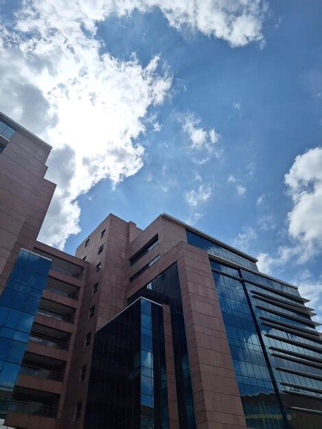 Un Edificio Con Una Fachada De Cristal Azul Y Un Cielo Azul Con Nubes