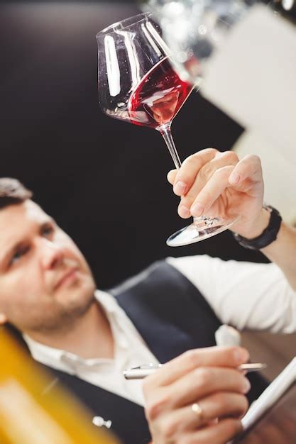 Un sommelier experto con bolígrafo mira el caro vino tinto natural en