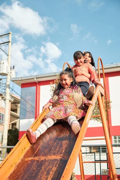 Premium Photo Three Very Happy Latina Girls Playing On The Slide At An Outdoor Park In Latin