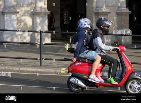 Two People Riding A Motor Scooter Towards Trafalgar Square In London