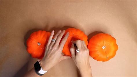 Two Oranges Being Held Up By Hands On Top Of A Beige Surface With Diamonds