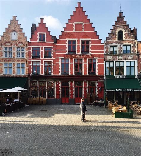 A Person Standing In The Middle Of A Cobblestone Street With Buildings