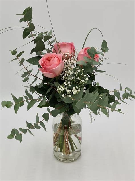 A Vase Filled With Pink Roses And Greenery