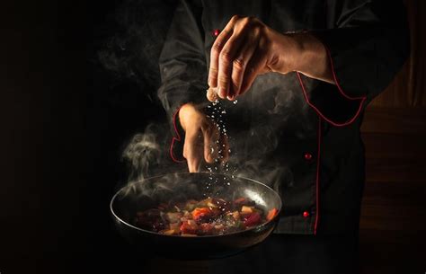 Premium Photo The Chef Adds Salt To A Steaming Hot Pan
