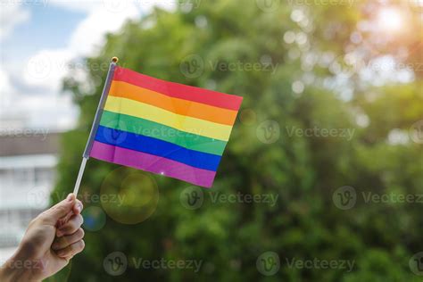 Hands Showing LGBTQ Rainbow Flag On Green Nature Background Support Lesbian Gay Bisexual