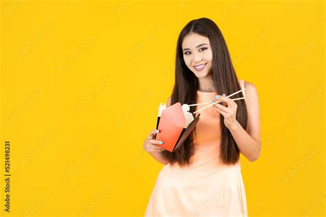 Young attractive asian woman eating asian wok food from paper wok box ...
