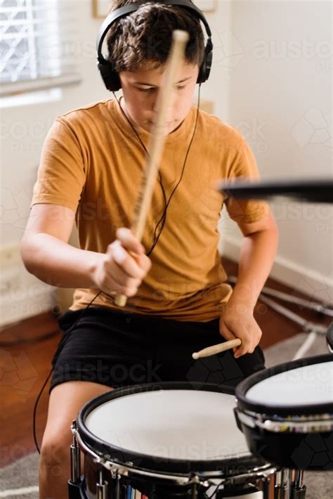 Image of teen boy practising drums at home - Austockphoto