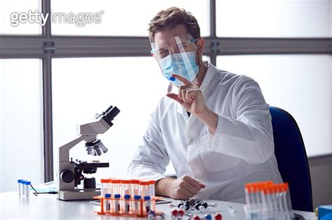 Male Lab Worker Wearing Ppe Analysing Blood Samples In Laboratory With