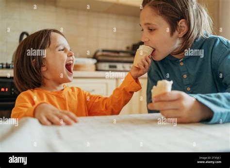 Happy boy feeding ice cream to brother at home Stock Photo - Alamy