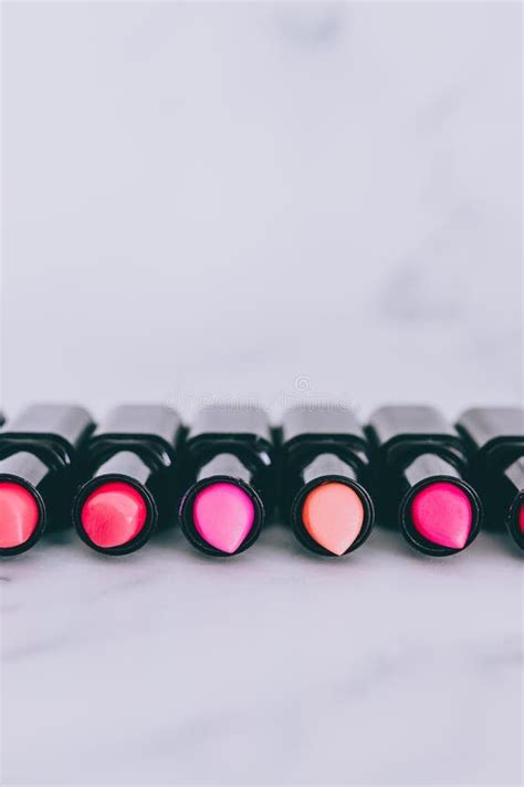 Group Of Red Pink And Nude Lipsticks With Different Colors And Textures Lined Up Lying On Marble