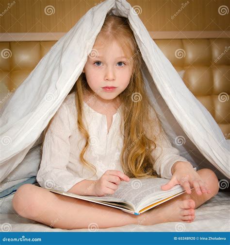 Little Girl Sitting on the Bed and Reading a Book Stock Photo - Image ...