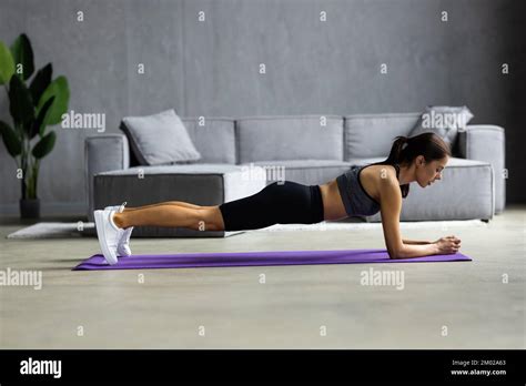 Slim fitnes young girl with ponytail doing planking exercise indoors at ...