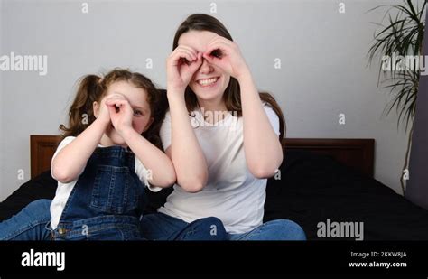 Mother And Comical Daughter Sitting On Bed Making Binocular Shape With Fingers Stock Video