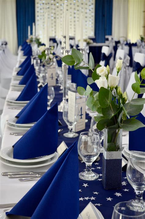 The Table Is Set With Blue And White Linens Silverware And Flowers