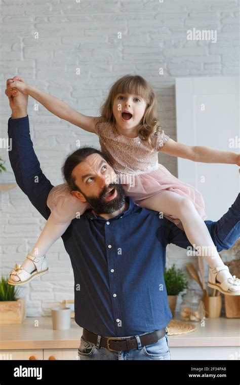 Happy Little Daughter Sitting On Father Neck Piggybacking Playing