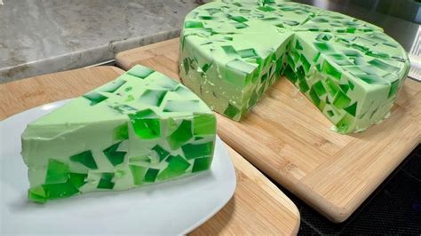 A Green Cake Sitting On Top Of A Wooden Cutting Board Next To A White Plate