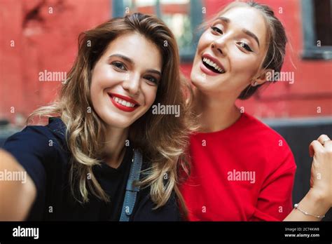 Two Young Beautiful Smiling Women Happily Taking Photos Together While