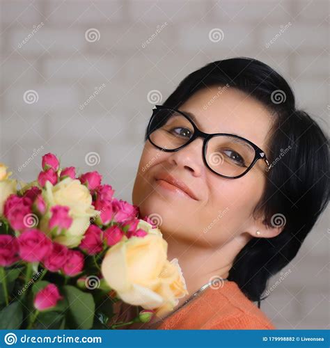 Een Jonge Mooie Gelukkige Brunette Vrouw In Een Bril Met Een Bloemetje Bloemen Kijkt Met Een