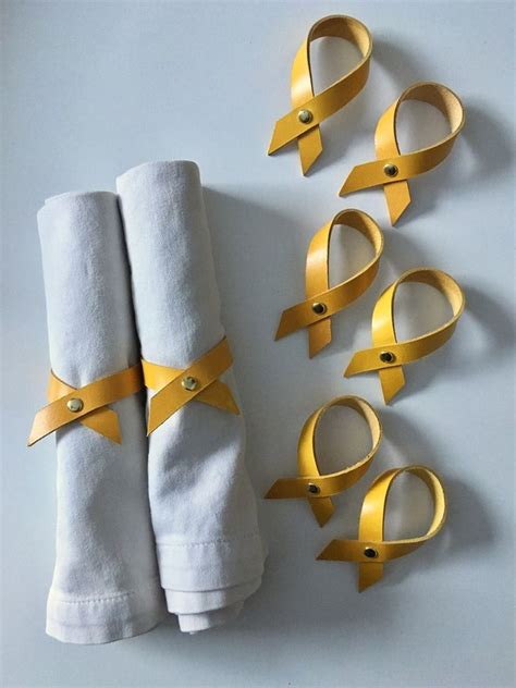 Folded Napkins With Gold Ribbon Tied Around Them On Top Of White Towels