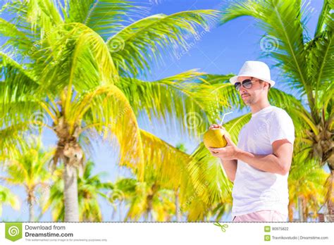 Young Man Drinking Coconut Milk On Hot Day On The Beach Stock Photo