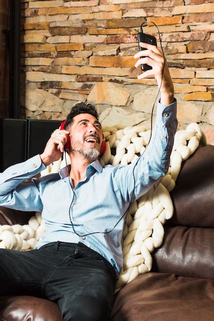 Free Photo Man Sitting On Sofa With Headphone On His Ears Making A