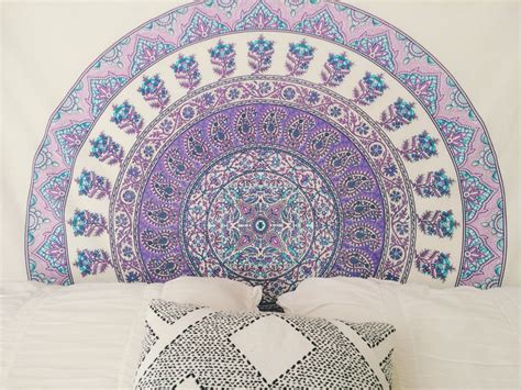 a bed with a purple and blue tapestry on the headboard next to two pillows