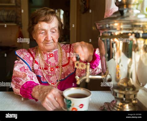 Grandmother In A Rural House Drinking Tea From A Russian Samovar Stock