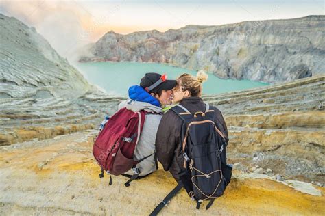 Un joven turista y una mujer se sientan al borde del cráter del volcán