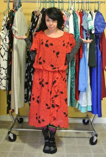 A Woman Standing In Front Of A Rack Of Clothes