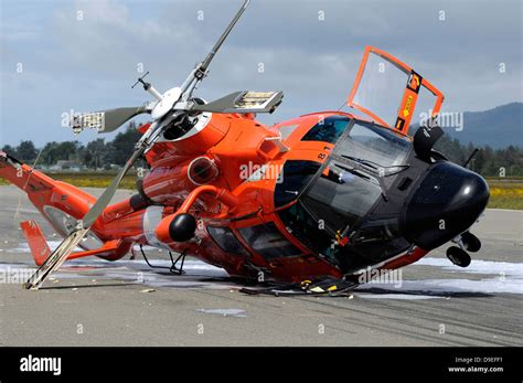 A U.S. Coast Guard MH-65 Dolphin helicopter lays on its side after it ...