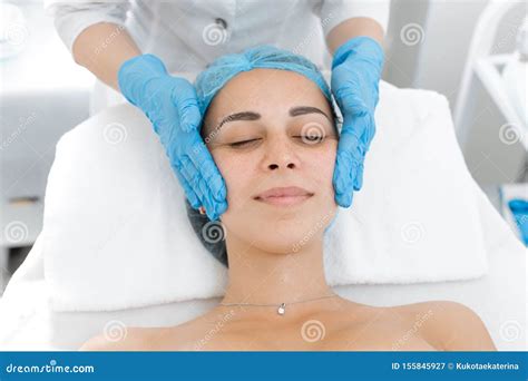 Beautician Makes Professional Massage Of The Patient`s Face A Young