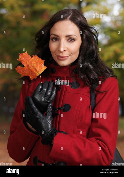 Portrait Of A Beautiful Woman Holding A Red Maple Leaf In Her Hands