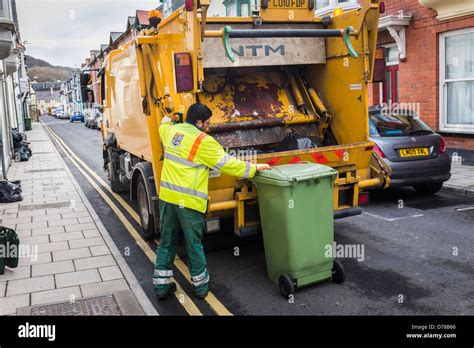 Local authority rubbish collection day - green wheelie bin being loaded ...