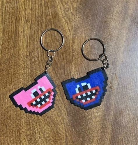 Two Pixel Keychains Are Sitting On A Wooden Surface One Is Pink And