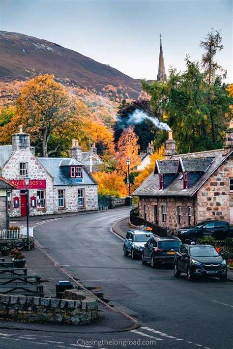 Cars Parked On The Side Of A Road In Front Of Buildings And Trees With