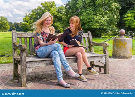 Girls Sitting On Wooden Bench In Park Reading Books Stock Image Image