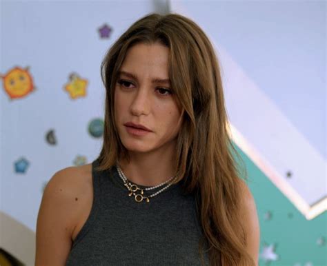 A Woman With Long Hair Wearing A Gray Top And Gold Chain Necklace On