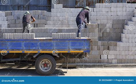 2 Asian Workers Are Loading Concrete Blocks Into The Truck For Delivery