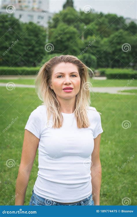 Stylish Blonde Woman In Jeans Shorts And A White T Shirt Posing For The