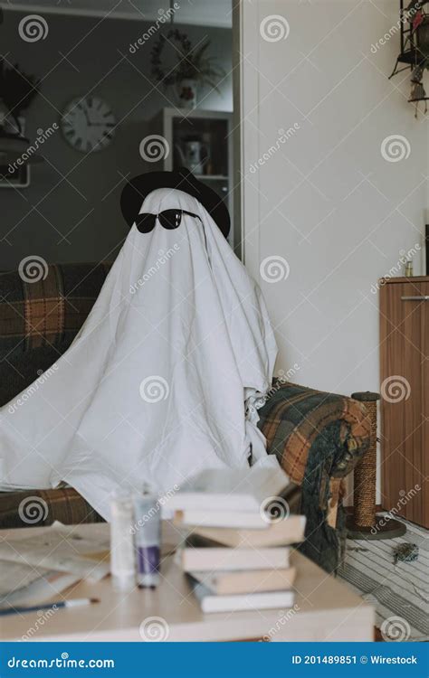 Person Wearing A White Bedsheet Over His Head With A Hat And Sunglasses Like A Ghost Stock Image