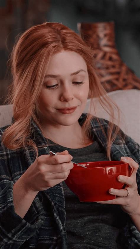 A Woman Sitting On A Couch Holding A Red Bowl