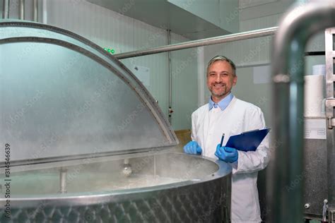 Smiling Dairy Plant Food Engineer Standing Beside Stainless Steel Milk