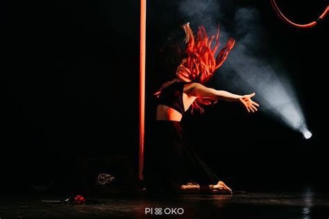 A Woman Standing On Top Of A Stage Next To A Pole With Fire In It