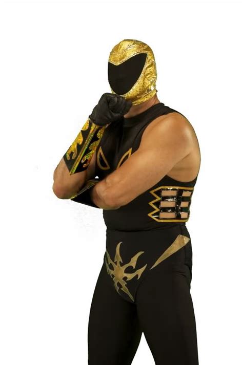 A Man In A Wrestling Suit With Gold Paint On His Face And Hands Behind