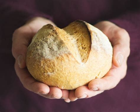 A Person Holding A Loaf Of Bread In Their Hands