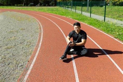 Lesión deportiva un joven asiático está sentado en el estadio en una