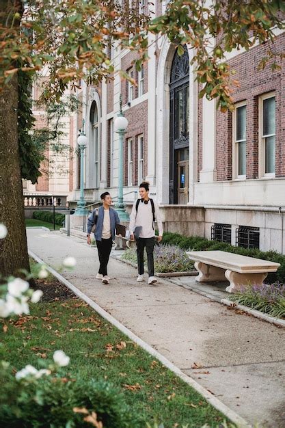 Premium Photo Two People Walking Down A Sidewalk In Front Of A Building